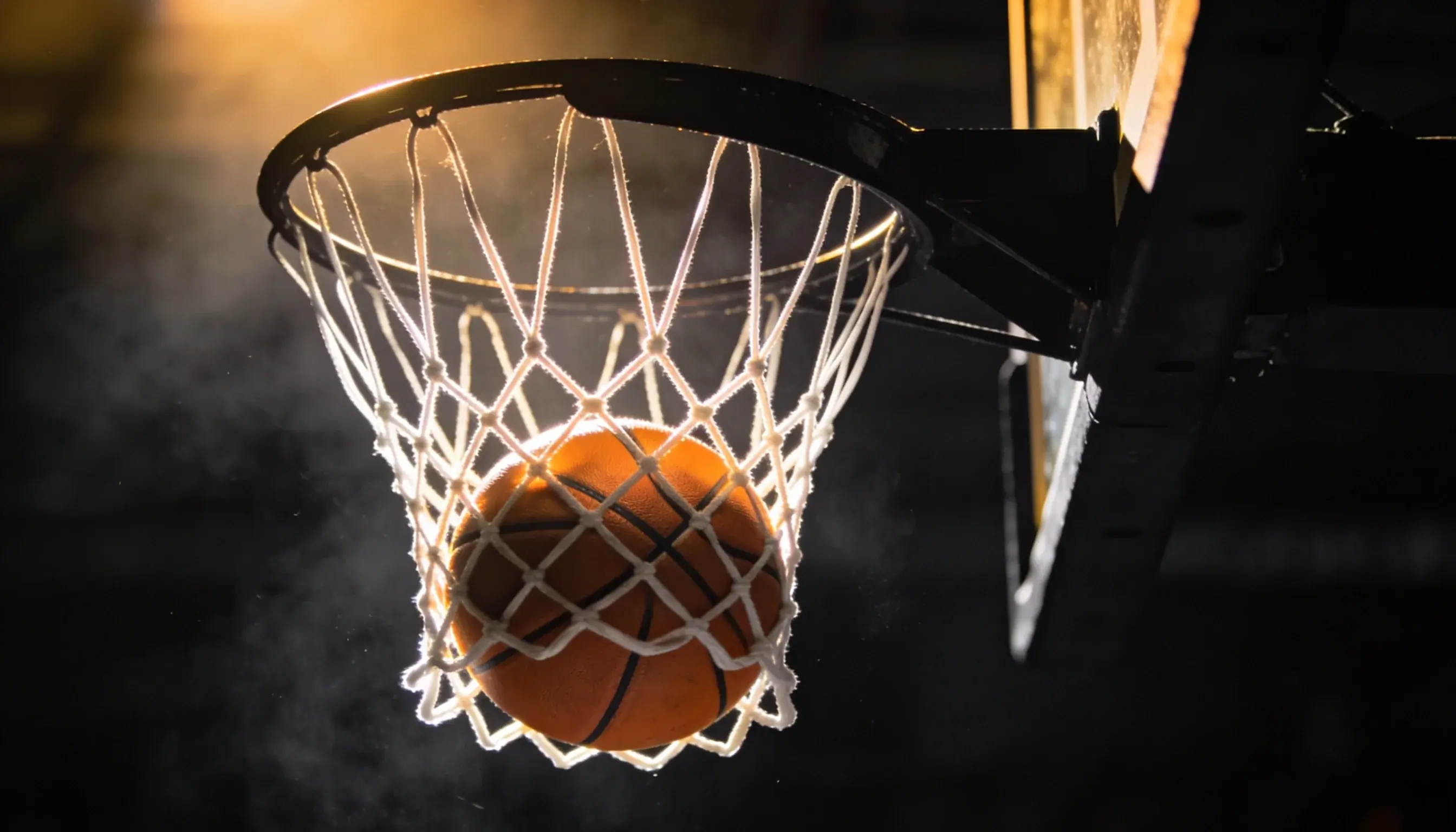 Basketball passing through a hoop in a UK arena at game time